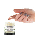 A hand with gray-painted nails holds a dollop of cream above an open jar labeled ProMeno Women's Wild Yam Cream against a white background.
