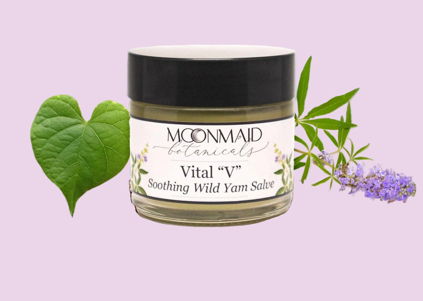 A jar of Vital "V" Wild Yam Salve rests on dried roots, alongside a green heart-shaped leaf and delicate purple flowers, with lush foliage in the background.