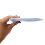 A hand holds the GoPee - Stand to Pee Device sideways against a white background, highlighting its discreet, compact, and portable silicone design.