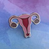 The OB/GYN Pin Pack features a colorful enamel uterus pin with detailed fallopian tubes and ovaries, shown on a purple-blue gradient—perfect for anatomy and OB GYN pin collections.
