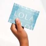 A hand holds a light blue packet of Lola 20ct Ultra Thin Pads w/ Wings, Regular, featuring the brand name in white letters on the packaging and offering reliable leak protection.