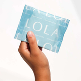 A hand holds a light blue packet of Lola 20ct Ultra Thin Pads w/ Wings, Regular, featuring the brand name in white letters on the packaging and offering reliable leak protection.