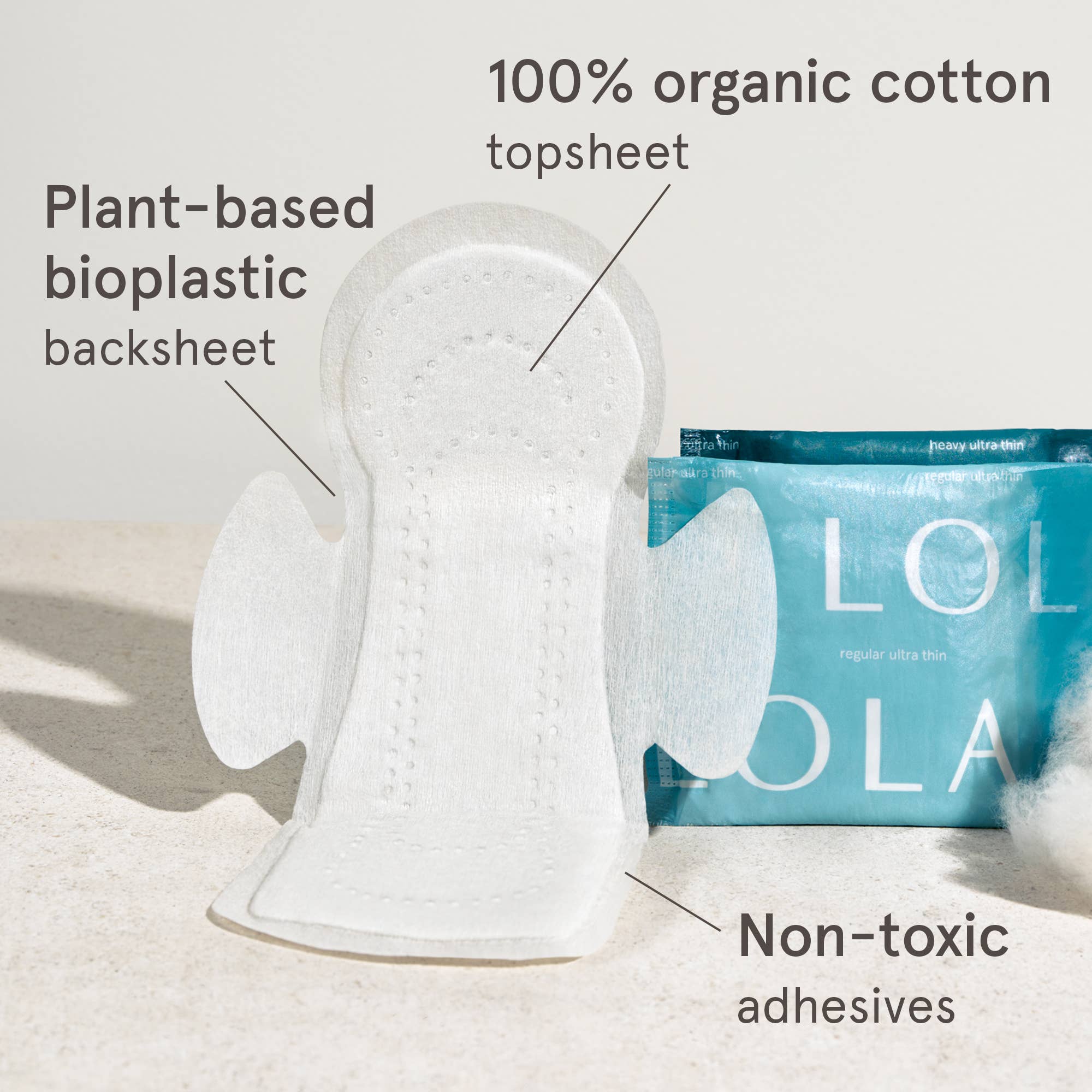 A Lola 20ct Ultra Thin Pad w/ Wings, Heavy is shown upright beside its teal box. Labels note: 100% organic cotton topsheet, plant-based bioplastic backsheet, non-toxic adhesives, and reliable leak protection.