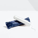 A wrapped and an unwrapped Lola 20ct Super Plus Tampon, made with organic cotton and a BPA-free applicator, are shown on a white surface against a plain white background.