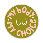 The My Body My Choice Sticker is a round green sticker with pink lettering around a white line drawing of a chest, featuring two dots for nipples—a bold statement supporting women's rights.