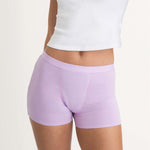 A person wearing Saalt Wear Leakproof Cotton Sleep Short in light purple with a white cropped top, shown from mid-torso to upper thighs against a plain background.