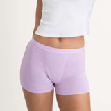 A person wearing a white crop top and Saalt Wear Leakproof Cotton Sleep Short in light purple, shown from mid-torso to upper thighs against a plain background.