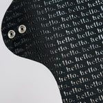 Black cloth pad with 'hello' text pattern on a white background and with metal snap wings