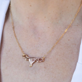 A Sterling Silver Uterus Necklace by Bang-Up Betty, featuring a delicate uterus-shaped pendant worn around the neck against light skin and a white shirt.