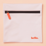 The Hello Wet Bag is a light pink waterproof storage bag featuring an orange zipper pull and "hello." printed in orange in the lower right corner, shown against a soft peach background.