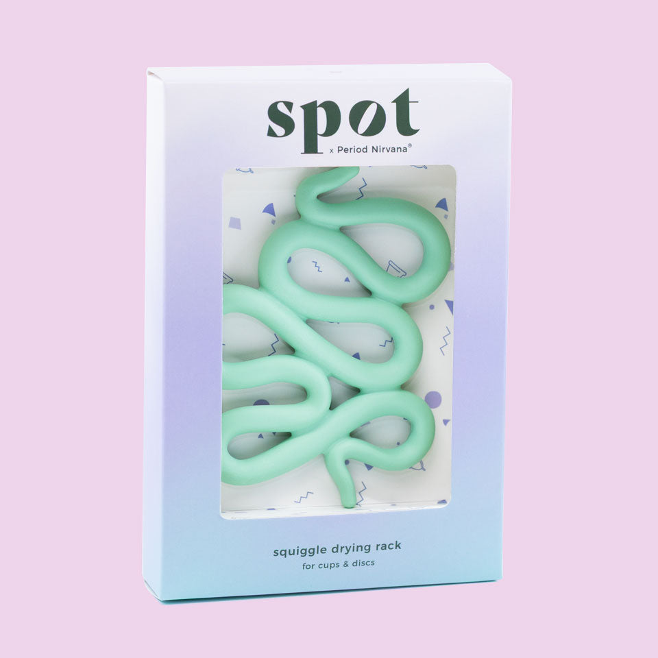 A pastel-colored box labeled Spot holds a mint green, squiggly silicone menstrual cup and disc holder, displayed on a light purple background.