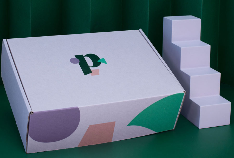 The Build Your Period Kit Bundle, in a rectangular white box with colorful geometric shapes and a stylized p logo, is displayed next to a four-step white staircase against a green background.