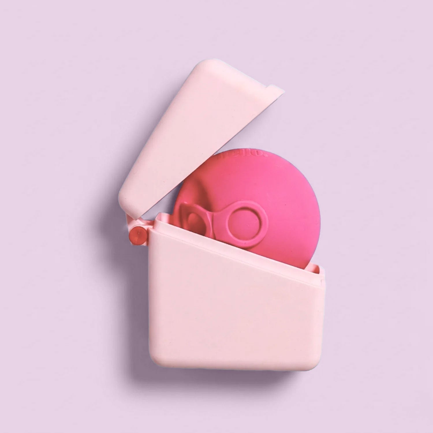 A pink spherical Hello Caddy with goggle-like features rests inside an open, light pink Hello Disc carry case that doubles as a microwave steriliser, set against a pastel lavender background.
