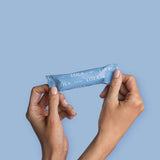 Two hands hold a box of Lola 20ct Super Tampons, featuring BPA-free applicators, against a solid light blue background.