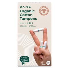 A 16-pack of DAME Organic Cotton Tampons is shown with a hand holding three non-applicator tampons. The vegan, hypoallergenic packaging states they're plastic-free, toxin-free, and offer super absorbency.