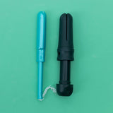 Two DAME Reusable Tampon Applicators, one blue and one black, are shown side by side on a green background. The blue applicator features a visible white string, highlighting a plastic-free period experience.