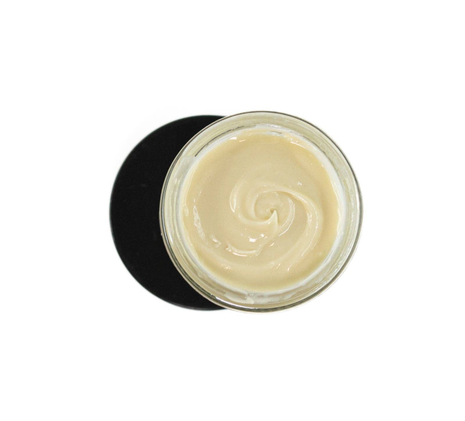 A glass jar of ProMeno Wild Yam Cream, with its creamy pale beige texture swirled smoothly, is viewed from above as it sits on a black circular surface against a white background.