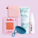 The Hello Disc Clean on-the-go Bundle is displayed on a pink background with a floral hello. wash tube, pink Hello Caddy box, mini spray, and blue silicone cup—ideal for your period cup cleaning kit.