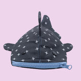 The Shark Week Pouch is a small, whale shark-inspired pouch with a blue zipper mouth, black button eyes, fins, and top fin. Its dark body features white cross patterns—ideal for storing period products or small items.