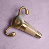 The Uterus Wine Stopper, featuring a gold-colored design, rests on a light gray textured surface—an ideal reproductive health-themed gift.