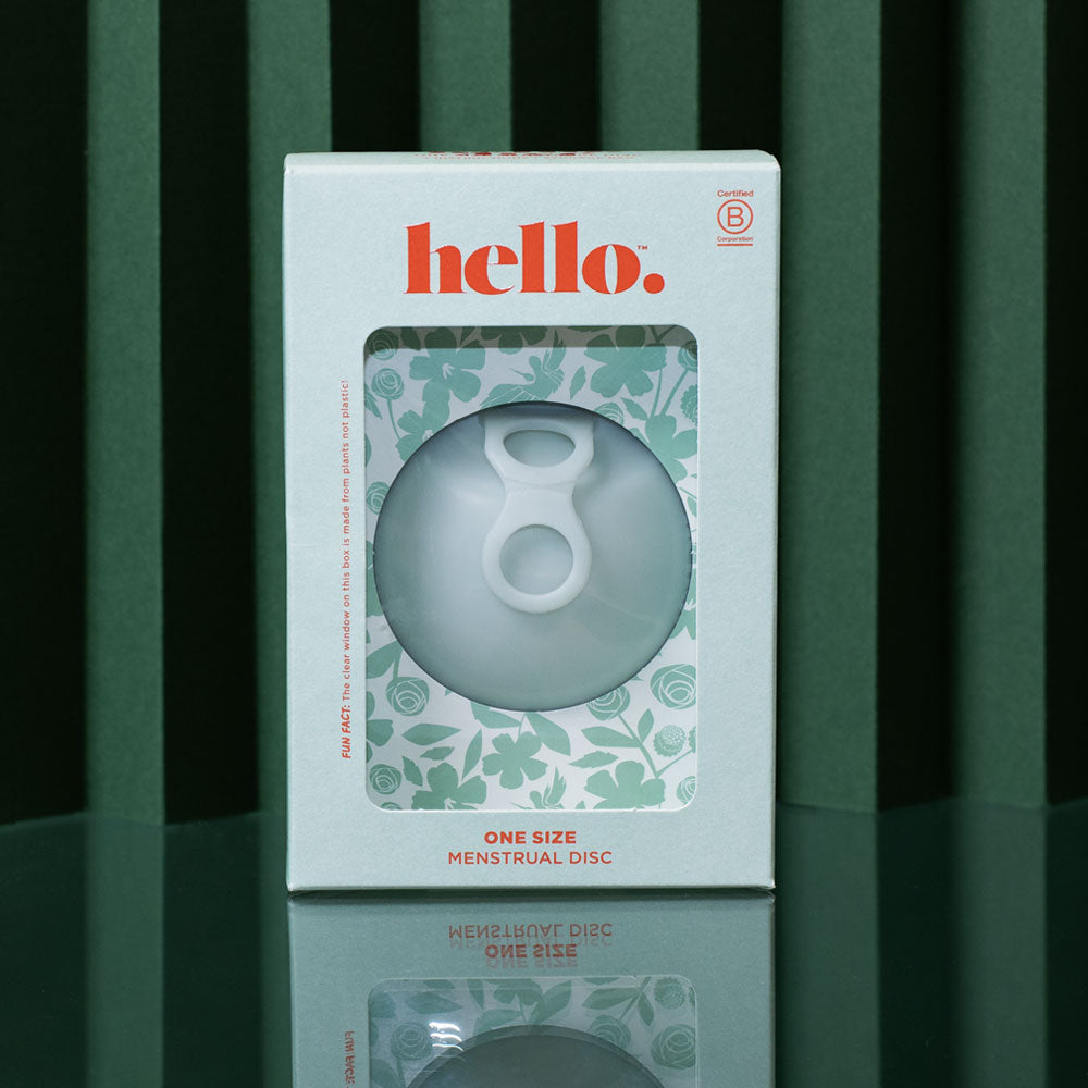 A box labeled hello. displaying the Hello Disc Clean on-the-go Bundle, a one-size menstrual disc starter set with floral-patterned packaging, is shown against a green background with vertical stripes.
