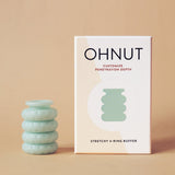 A set of four light green, stackable Ohnut Buffer Rings sits beside its beige and white box labeled "Ohnut: Penetration Depth Control." The stretchy, body-safe silicone rings are displayed on a neutral background.