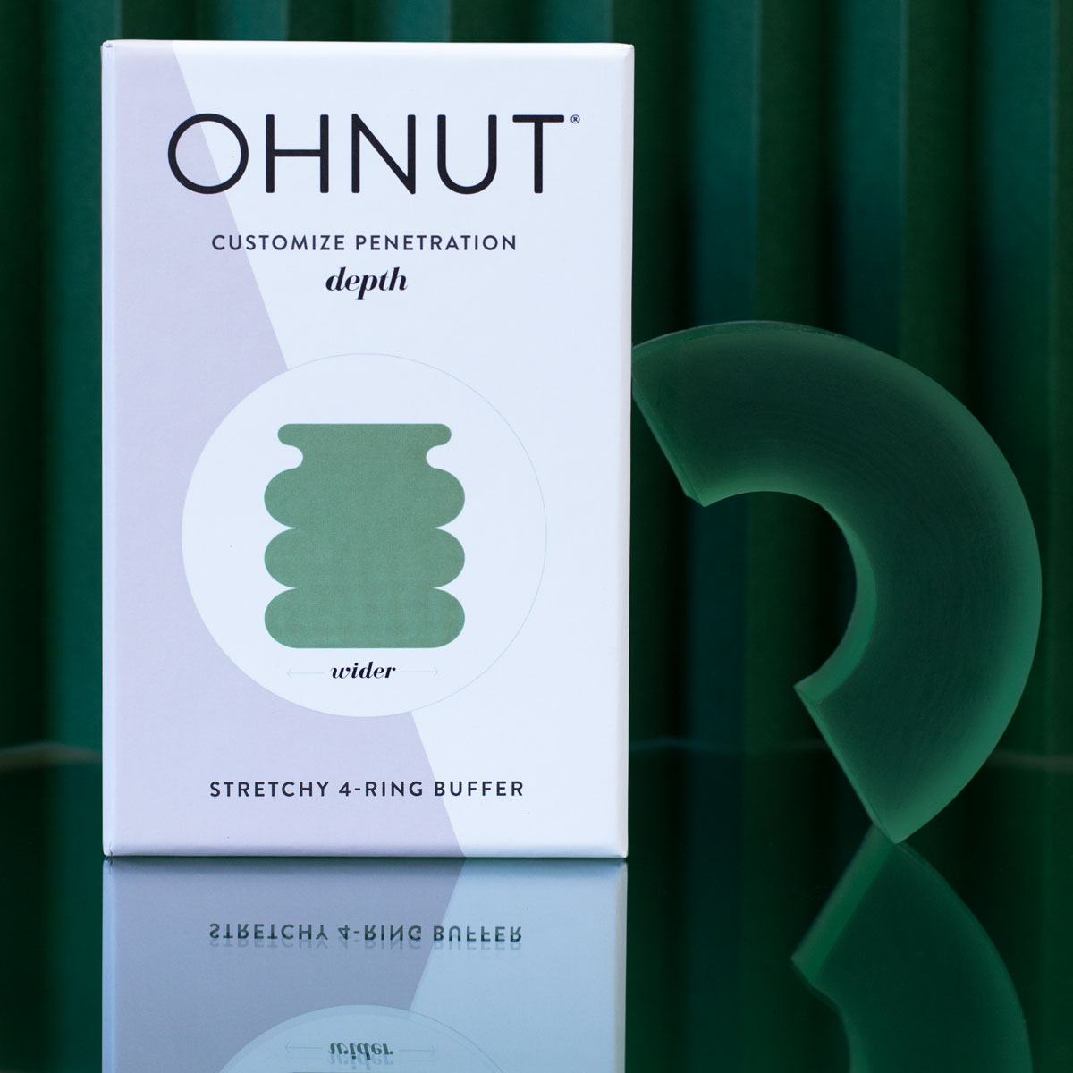 A box labeled Ohnut Buffer Rings - Set of 4 stands on a reflective surface beside a green, curved silicone ring. The packaging highlights four body-safe rings and a diagram showing customizable penetration depth.